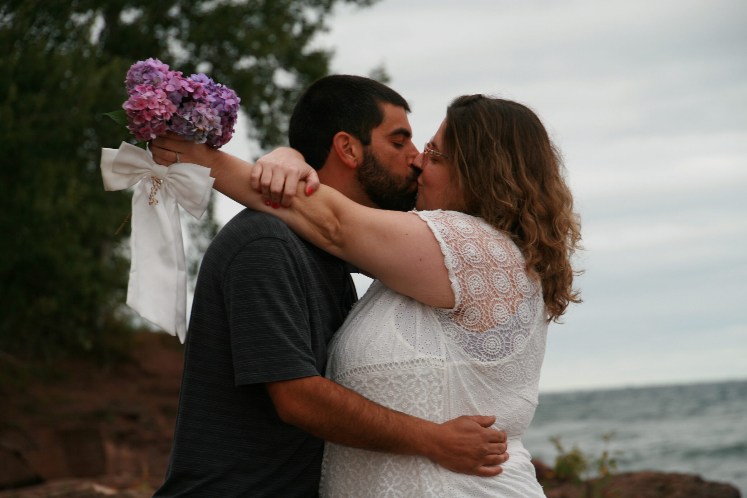 Tessa and Julian sharing a kiss by the water